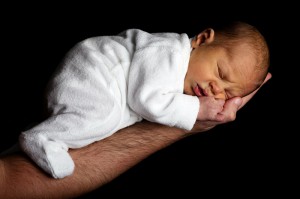 Brazo de hombre sujetando a bebé dormido