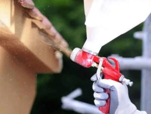 persona aplicando una capa de corcho proyectado con pistola profesional sobre la superficie exterior de una pared